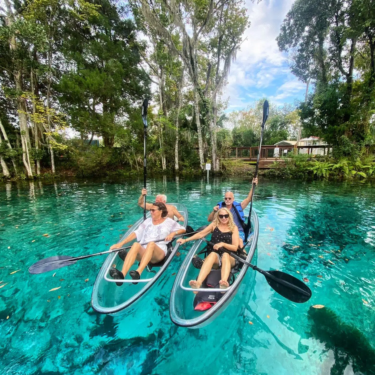 Two tandem clear kayaks side by side on a turquoise spring